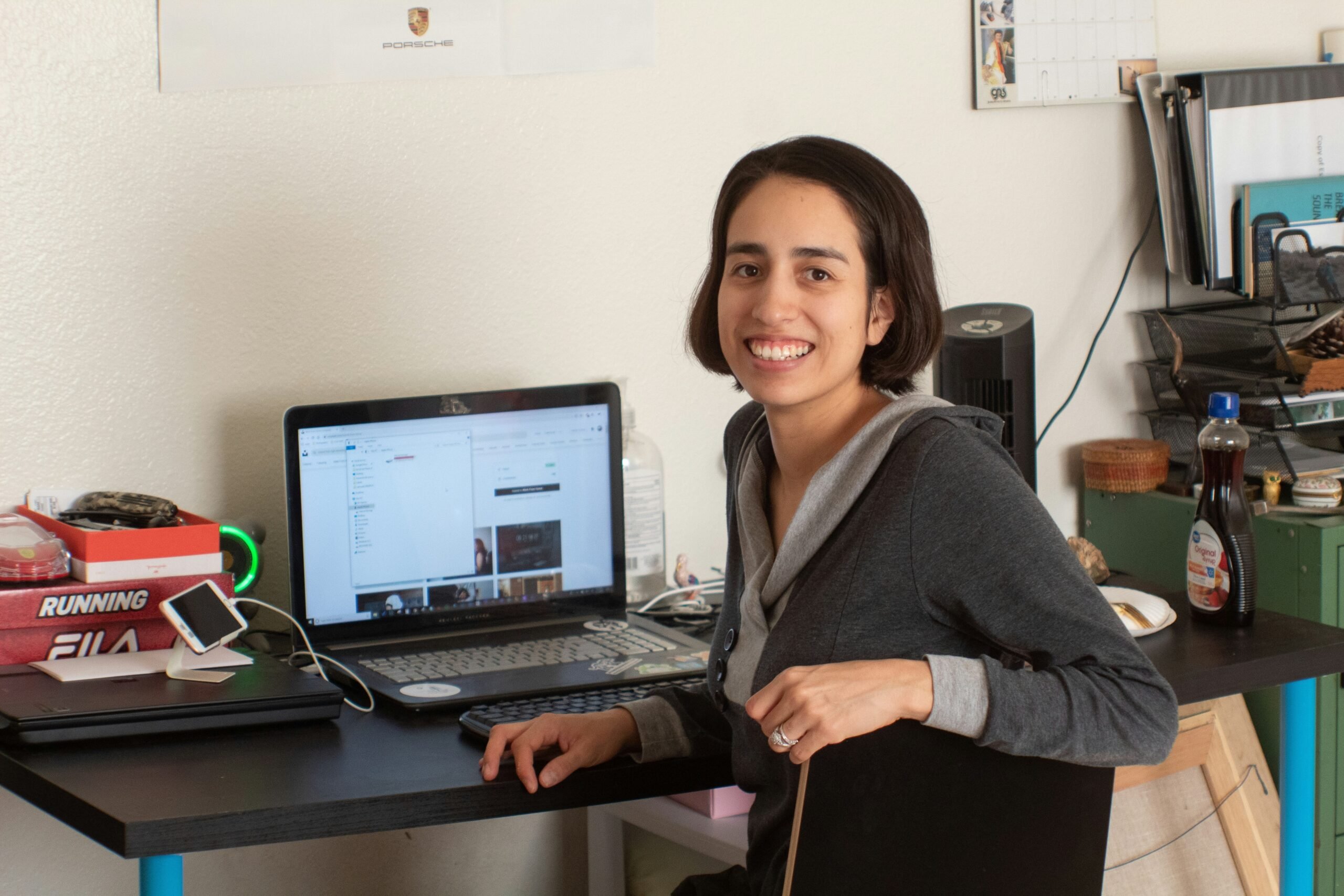 Sarah smiling next to a laptop displaying organized spreadsheets